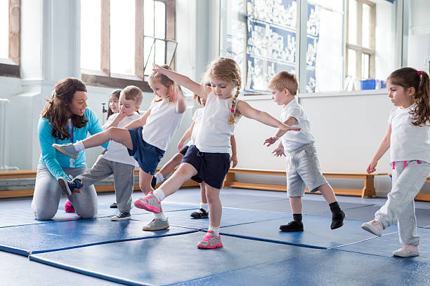 Nursery teacher helping one of her students during a physical education lesson.